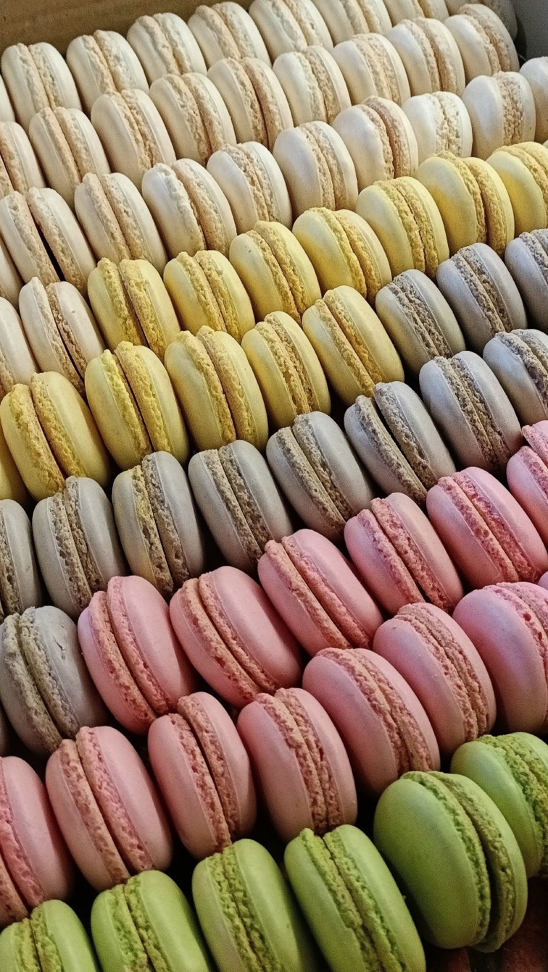 Rządowo ułożone francuskie makaroniki w pastelowych odcieniach bieli, żółci, różu i zieleni.