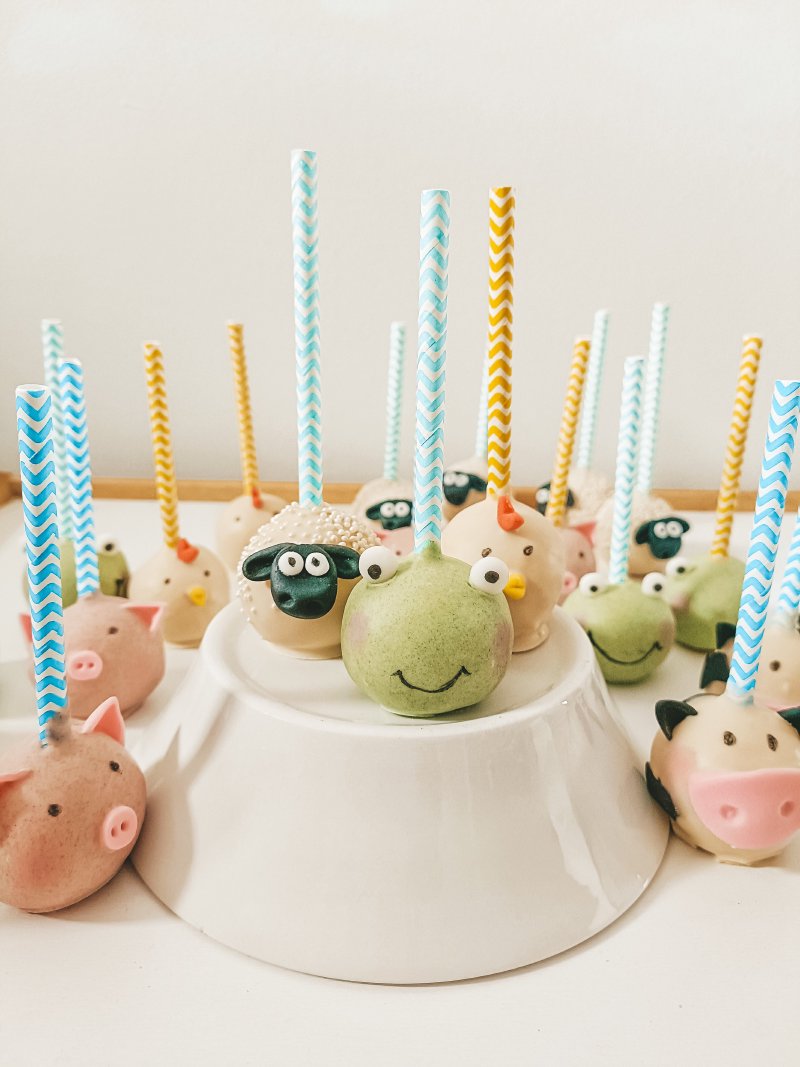Zestaw cake popsów w kształcie zwierzątek farmy na słodkim stole.