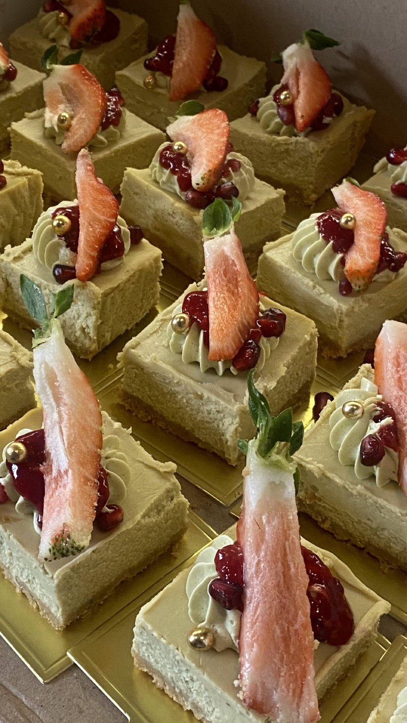 Rząd kwadratowych deserów matcha udekorowanych świeżymi truskawkami