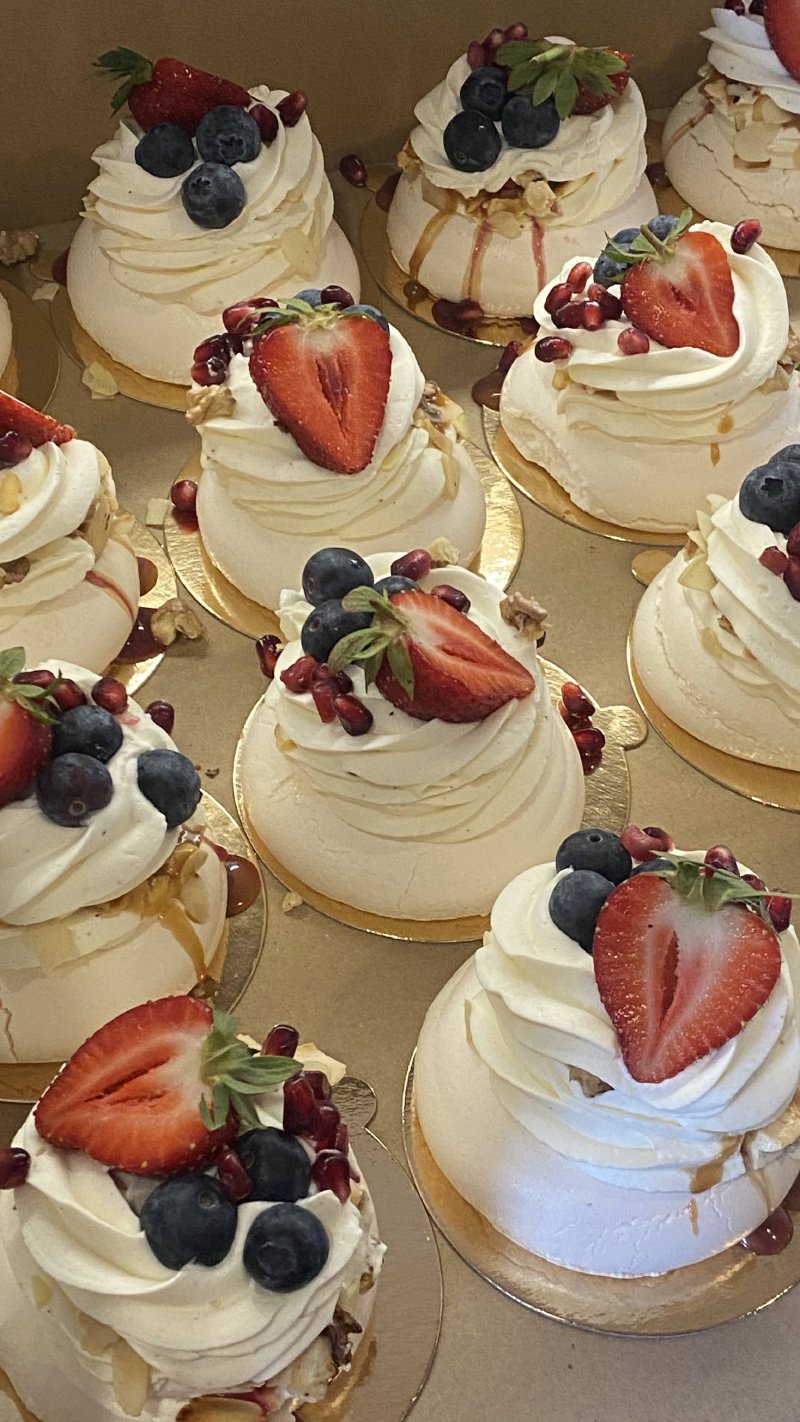 Rząd miniaturowych bez Pavlova dekorowanych truskawkami i borówkami