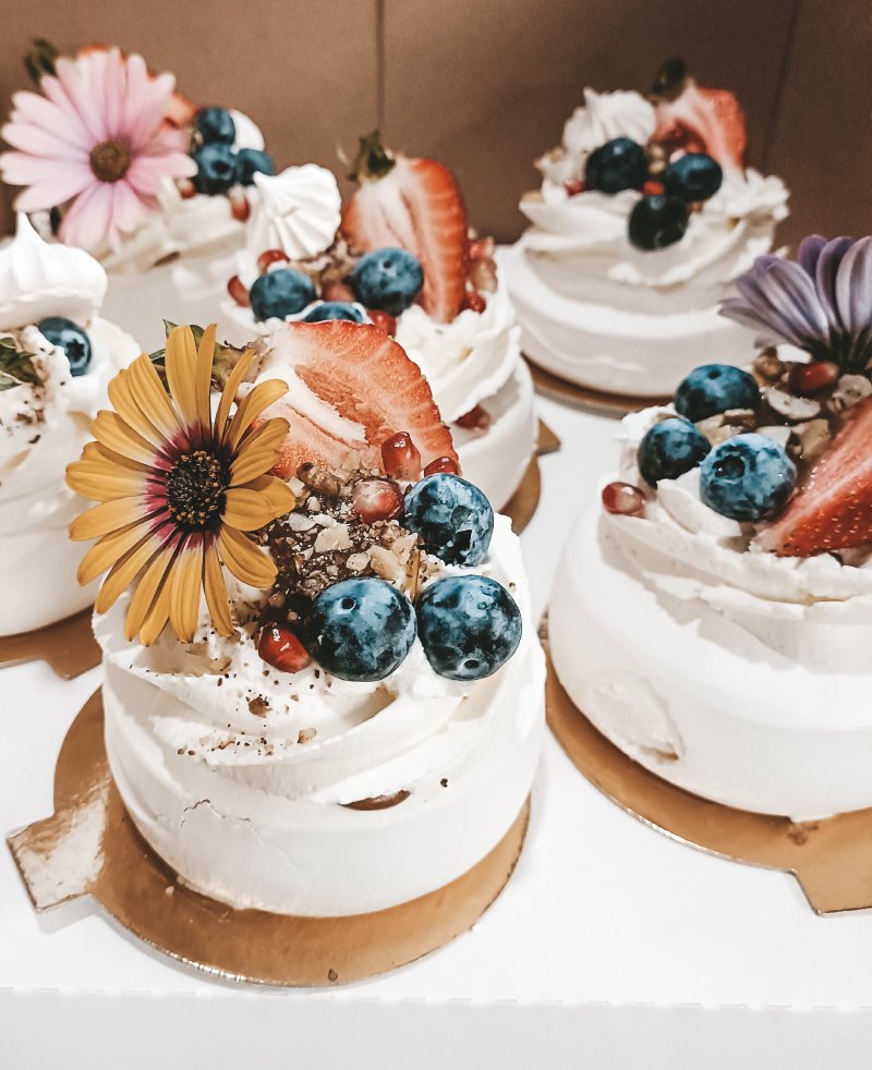 Zestaw mini deserów Pavlova z bitą śmietaną, borówkami i kwiatami