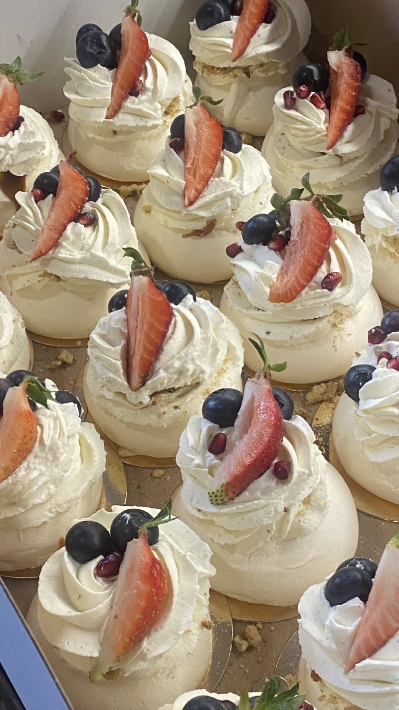 Zestaw miniaturowych bez Pavlova z białą kremową masą i dekoracjami z truskawek.
