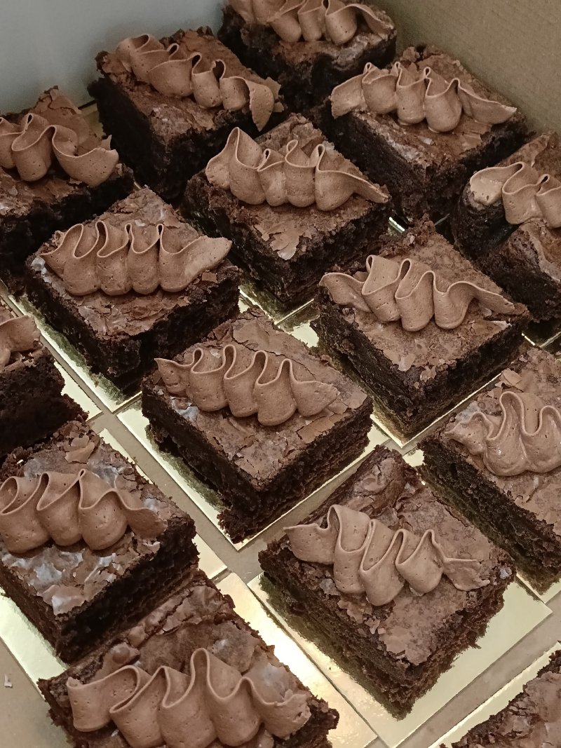 Zestaw kwadratowych, intensywnie czekoladowych brownie z kremową dekoracją