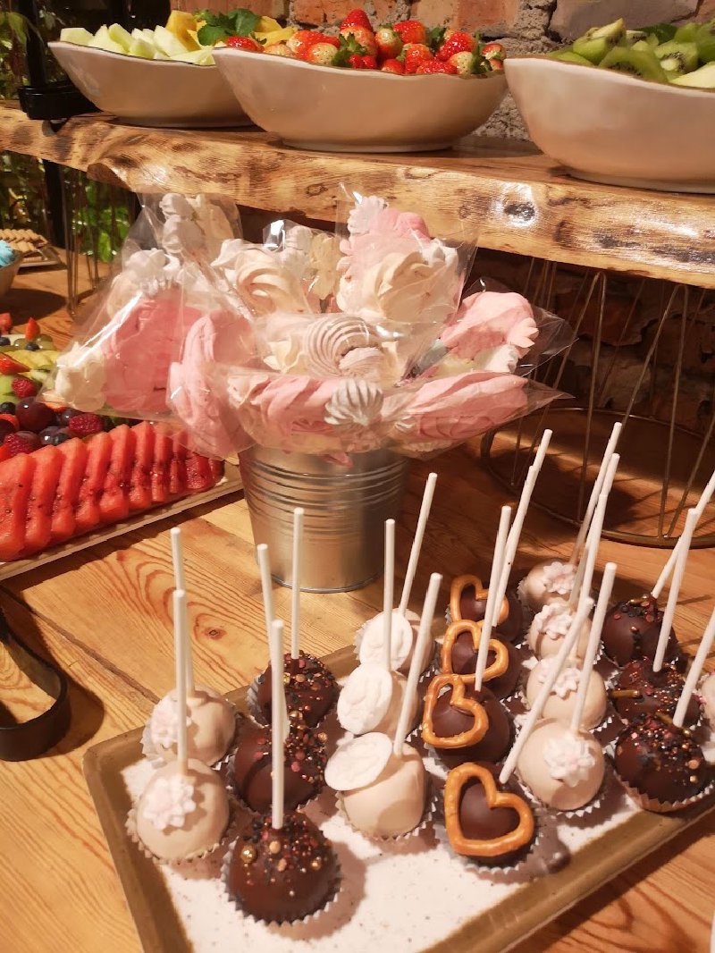 Słodki stół z czekoladowymi cake popsami i różowymi bezami