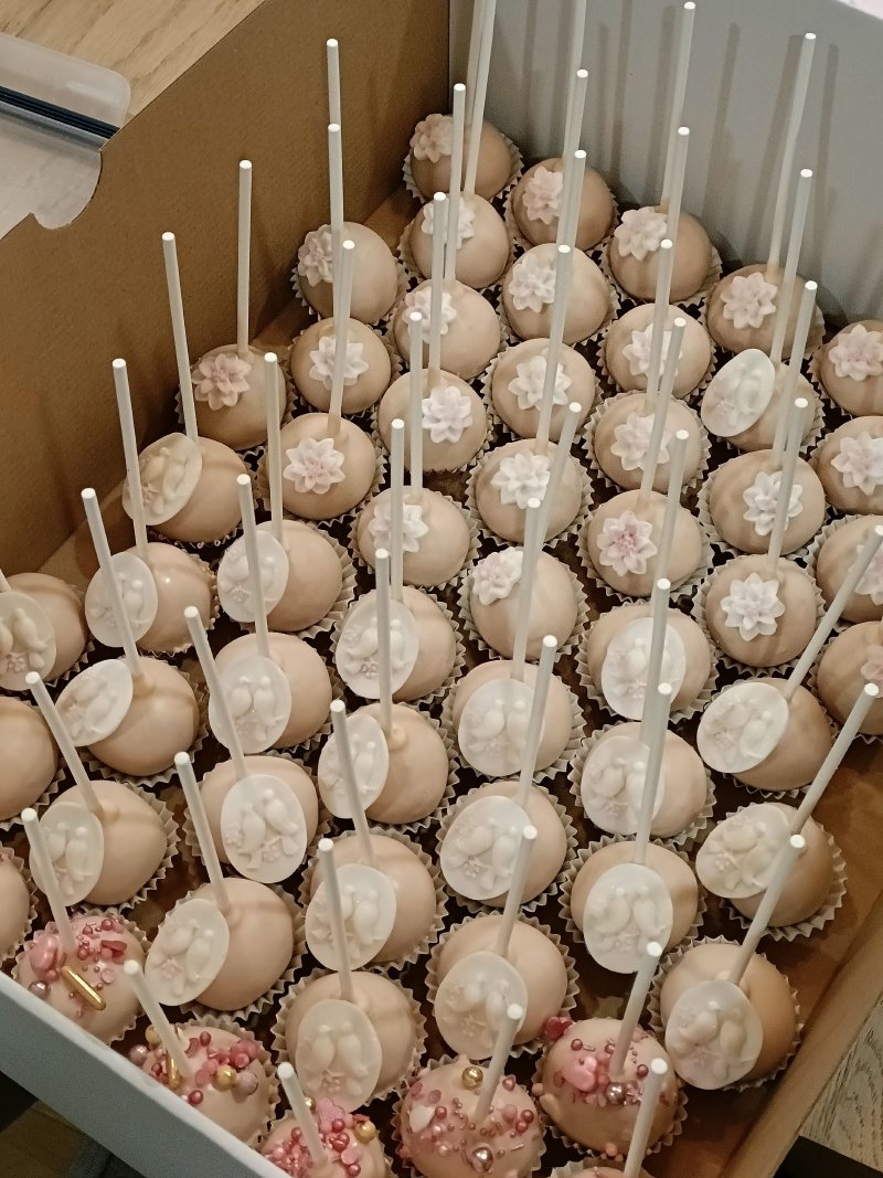 Duży zestaw różowych cake popsów zdobionych cukrowymi kwiatami i perełkami