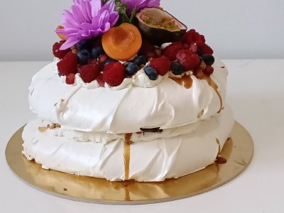 Dwupiętrowa beza Pavlova udekorowana świeżymi owocami i kwiatami