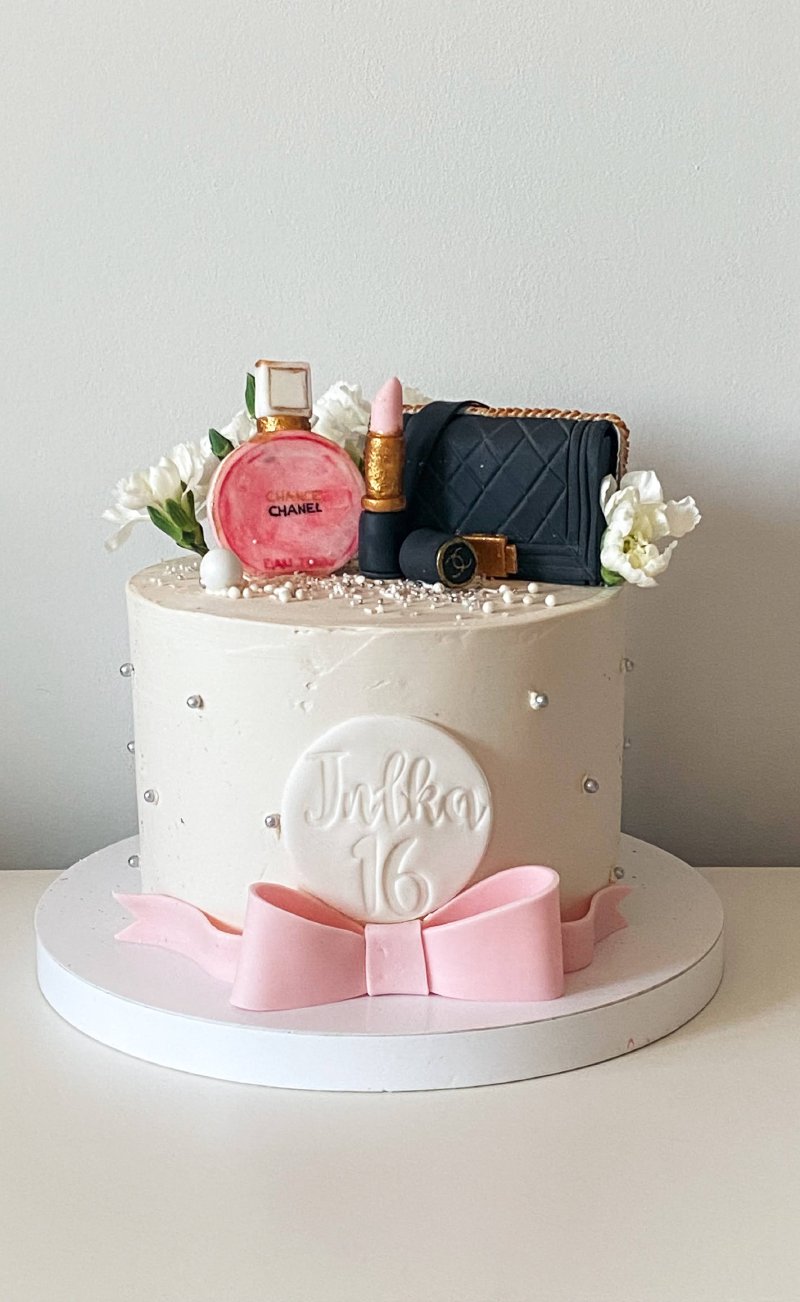 Biały tort urodzinowy dla Julki na 16 lat z dekoracjami w stylu Chanel i różową kokardą.