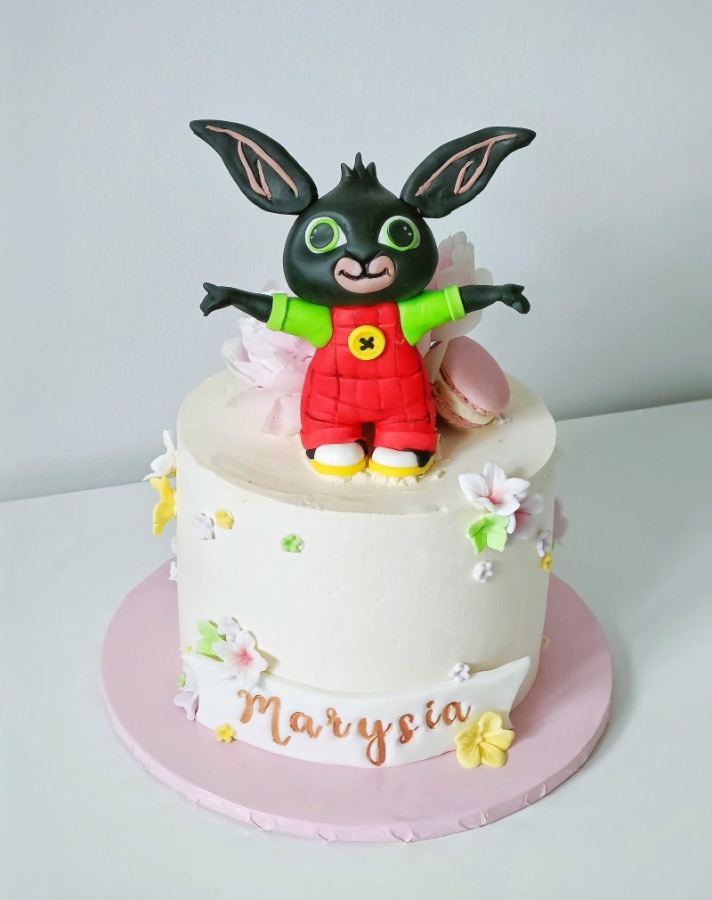 Biały tort urodzinowy z figurką królika Binga i personalizowanym napisem 'Marysia'.