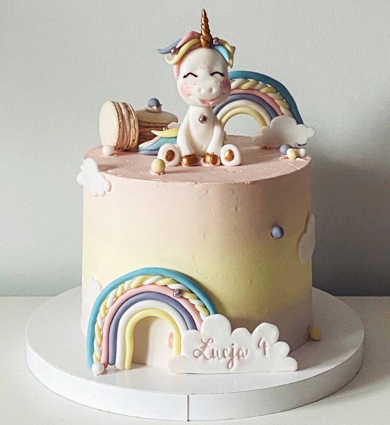 Wysoki tort urodzinowy z jednorożcem i tęczą w pastelowych kolorach