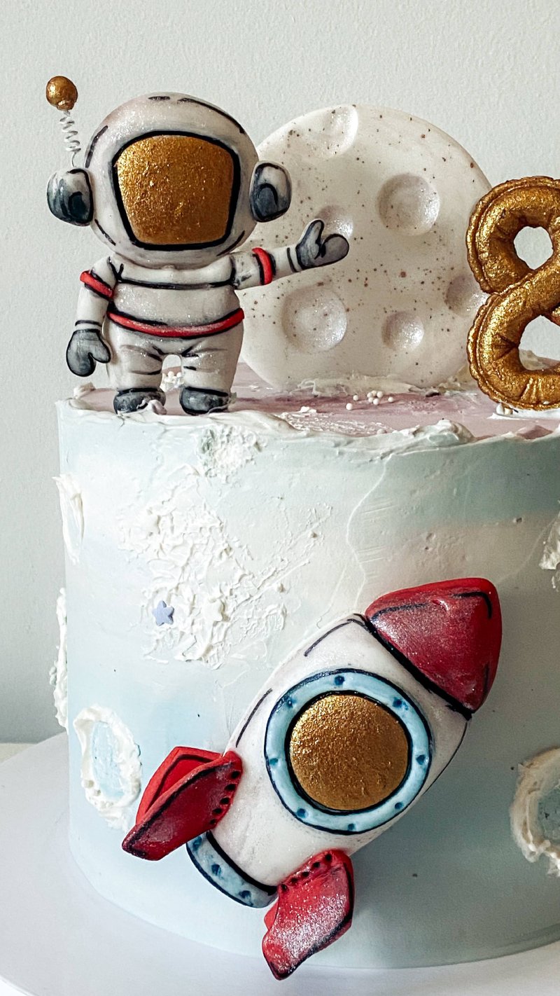 Kawałek tortu urodzinowego z dekoracją astronauty, rakiety i księżyca