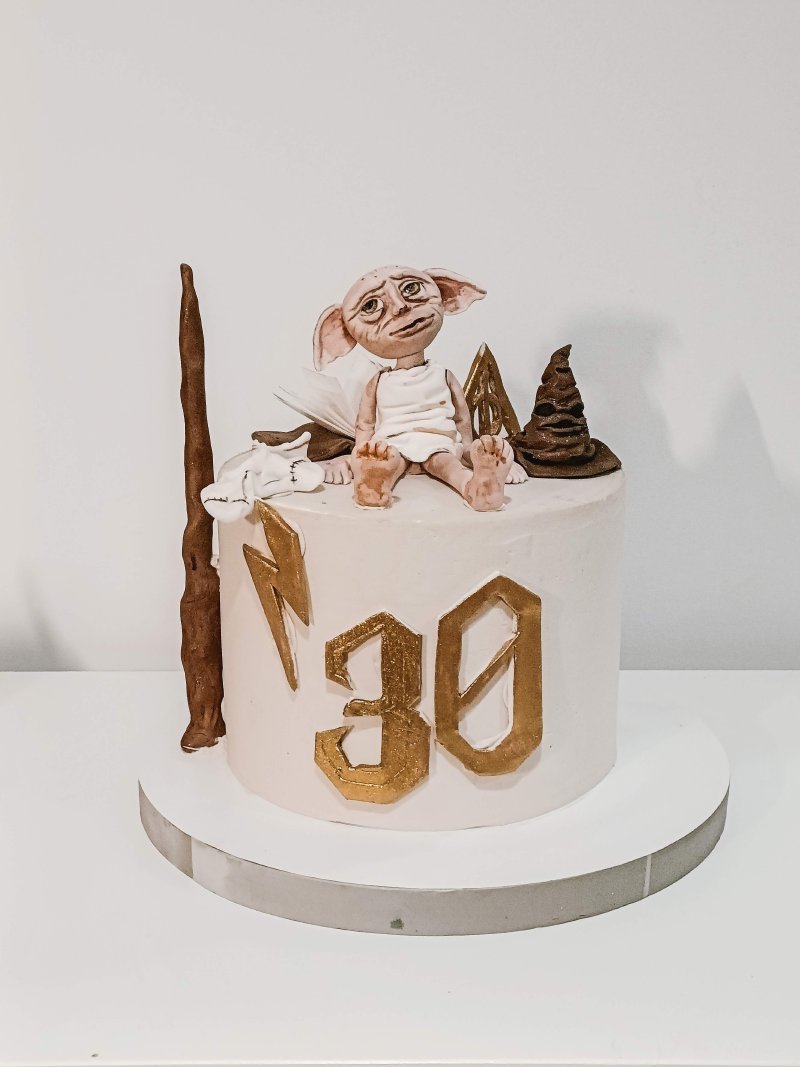 Elegancki tort urodzinowy z figurką Dobby'ego i złotymi liczbami 30.