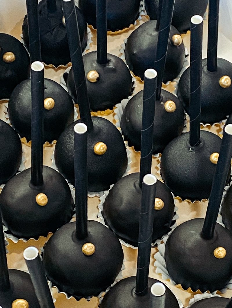Zestaw czarnych cake popsów ze złotymi detalami na czarnych patyczkach