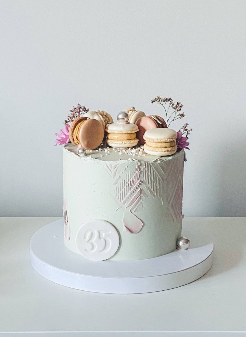 Elegancki tort urodzinowy ozdobiony makaronikami i kwiatami z cyfrą 35