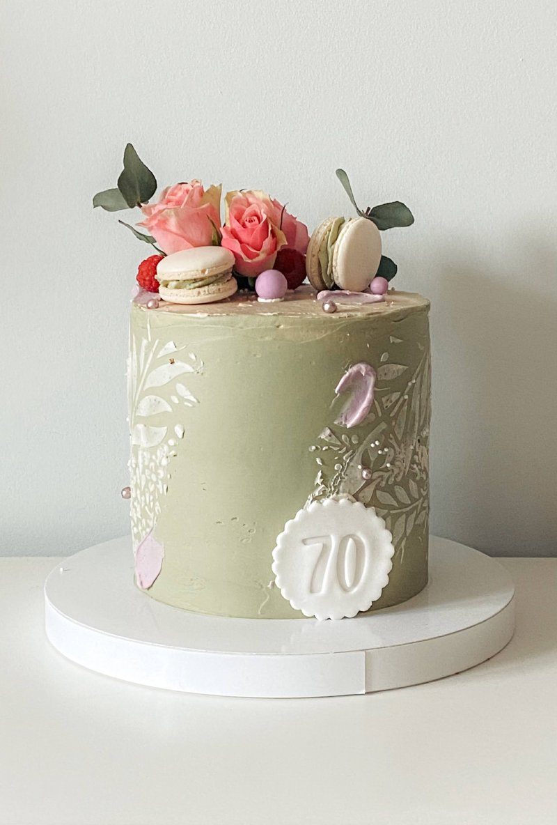Elegancki tort na 70. urodziny w kolorze szałwiowym z różami i makaronikami.