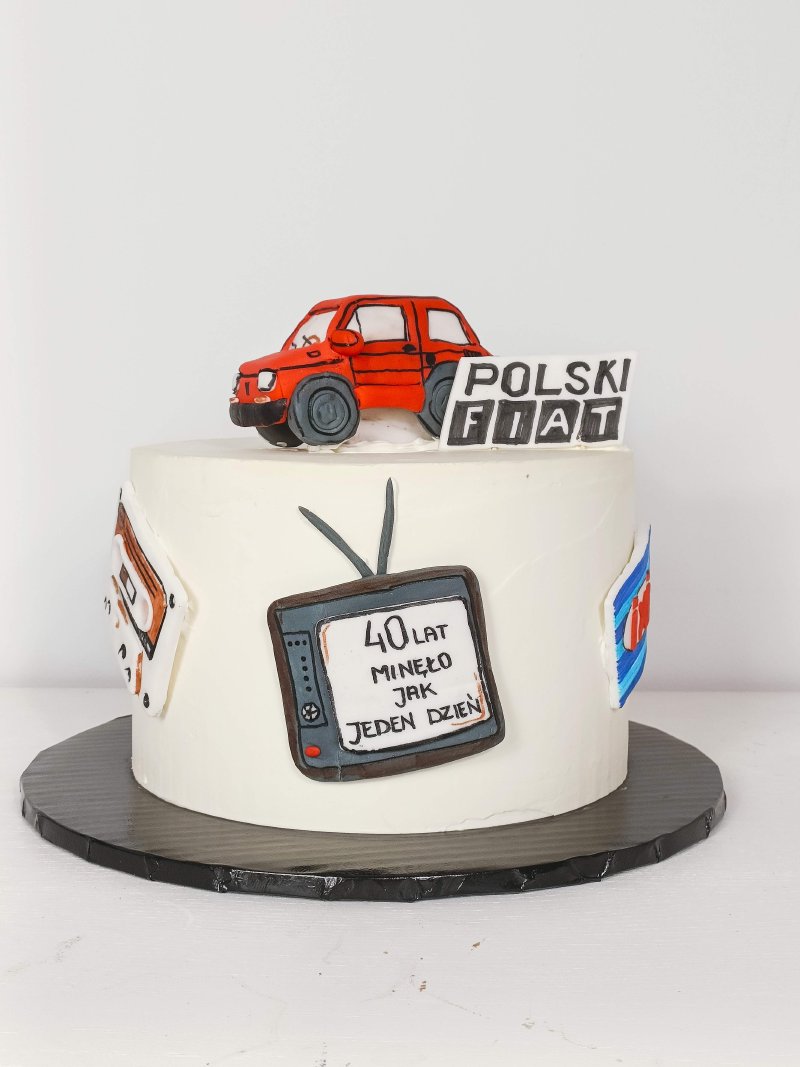Biały tort urodzinowy z figurką czerwonego Polskiego Fiata i dekoracjami retro.