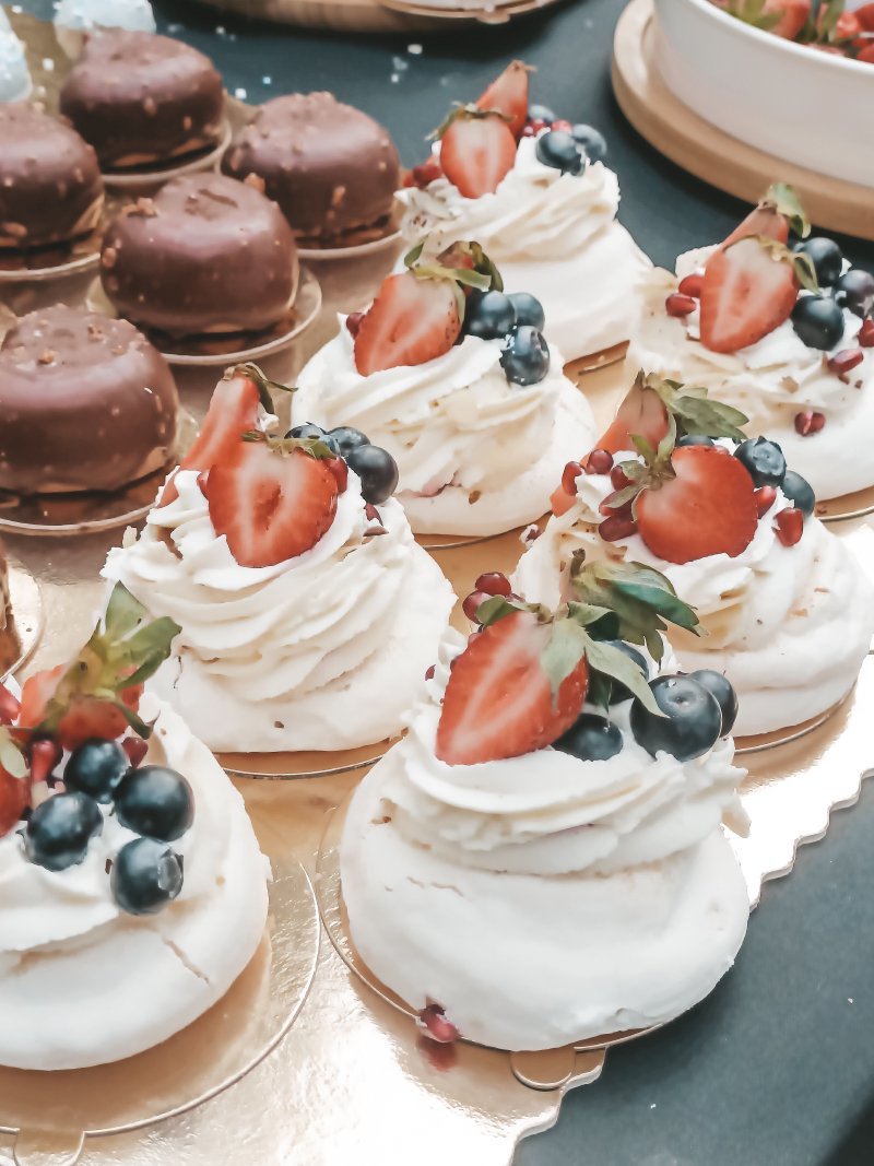 Zestaw mini bez Pavlova udekorowany szafirsymi owocami i truskawkami.