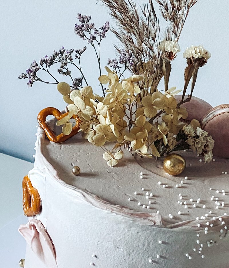 Ozdobiony tort z kremową polewą i suszonymi kwiatami w stylu boho