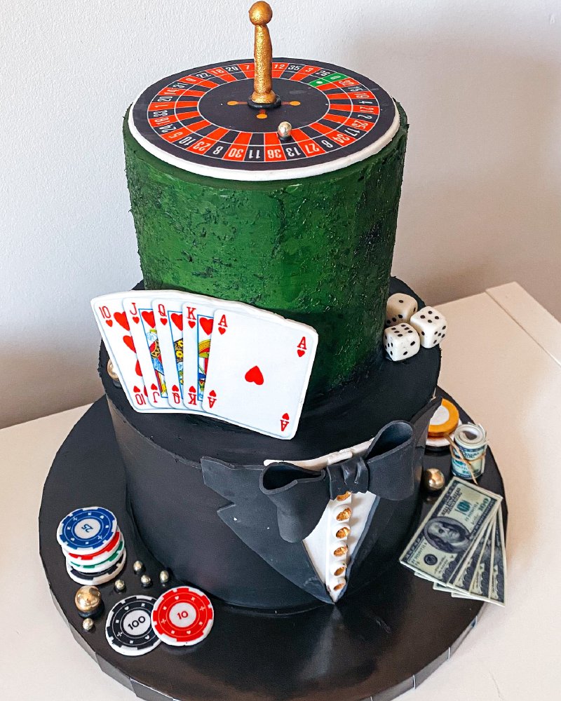 Dwupoziomowy tort artystyczny o tematyce kasyna z topperem ruletki i dekoracjami pokerowymi.