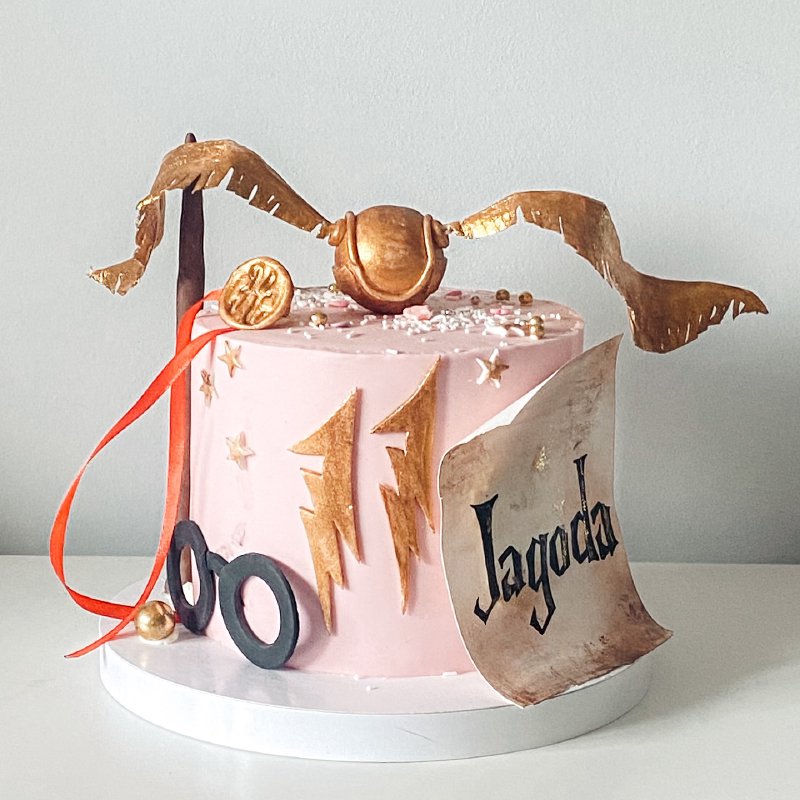 Różowy tort urodzinowy z dekoracjami tematycznymi z Harry'ego Pottera