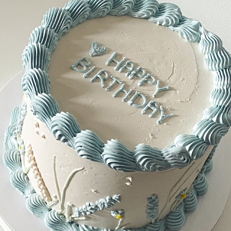 Tort urodzinowy z napisem 'Happy Birthday' i błękitnymi falistymi rantami