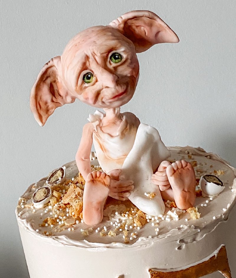 Tort udekorowany cukrową figurką Dobby'ego siedzącego na wierzchu